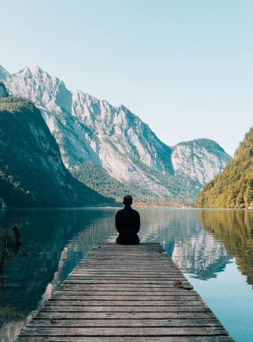 Person sitting on a dock overlooking the water.