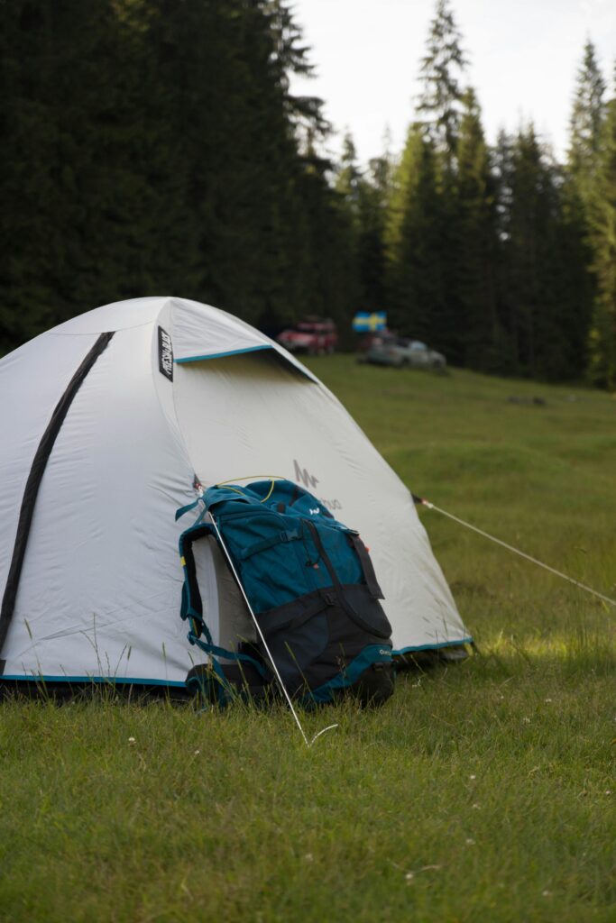 A serene campsite with a tent and backpack in the scenic Padiş forest, Romania.